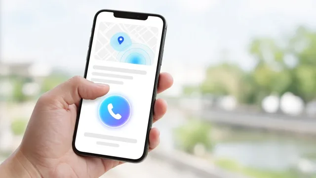 Kézben tartott telefon, a hüvelykujj a nagy hívógombra koppint, felette térképes helymegosztás
